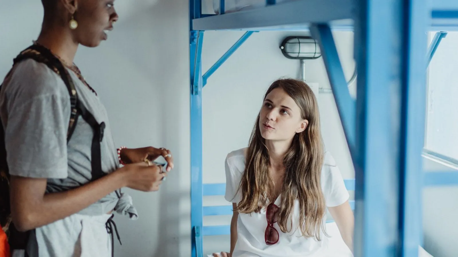 Two travellers talking in a hostel dorm